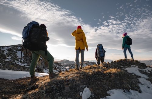 Four unrecognizable hikers are relaxing on mountain top